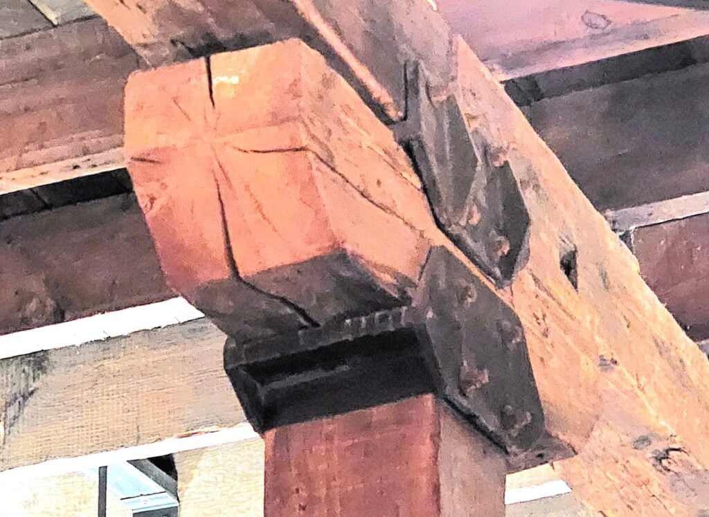 Structural beam bearing load distribution on wooden post