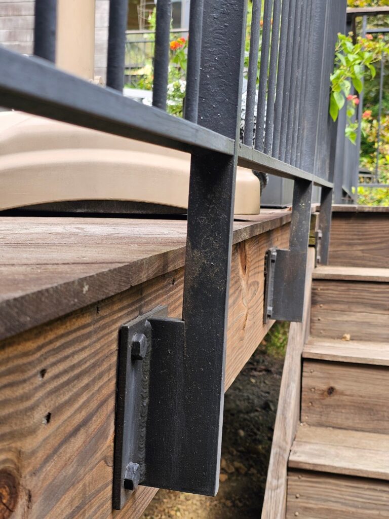 Close-up of metal handrail brackets attached to a wooden deck