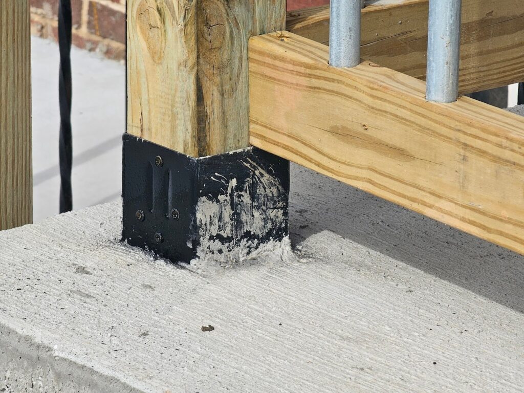 Craftsman securing electrical tubing to wooden deck guardrail